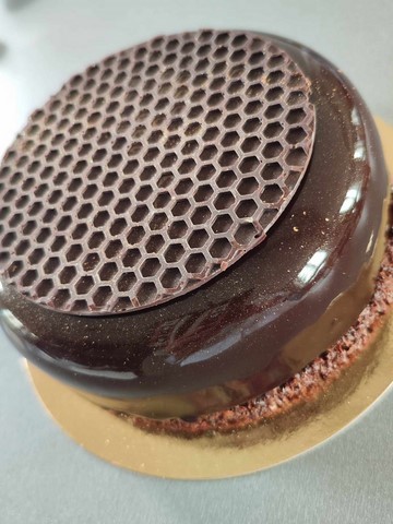 Entremet au chocolat noir avec insert coulant praliné, sur biscuit croustillant reconstitué, et nappé d'un glaçage miroir chocolat noir