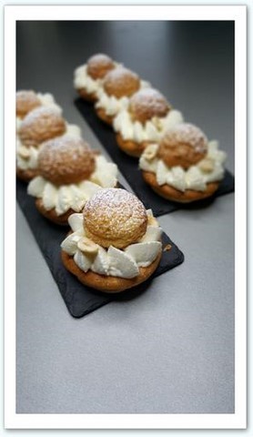 Une couronne de chou dressée sur une pate feuilletée, garnie d'une crème pâtissière au praliné, de chantilly vanille, d'un coeur coulant au praliné et surmonté d'un chou craquelin garni