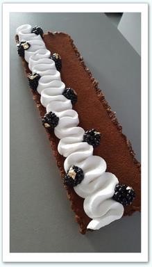 Coque crousti-moelleuse aux fruits secs garnie d'une ganache cacao et sirop d'érable avec une touche de café, décoré d'une rosace de chantilly coco et mûres