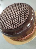 Entremet au chocolat noir avec insert coulant praliné, sur biscuit croustillant reconstitué, et nappé d'un glaçage miroir chocolat noir